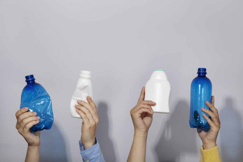 mani che tengono bottiglie di plastica vuote